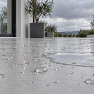 Piso exterior de microcemento protegido con Finish WP bajo la lluvia: el agua queda en gotas y no mancha